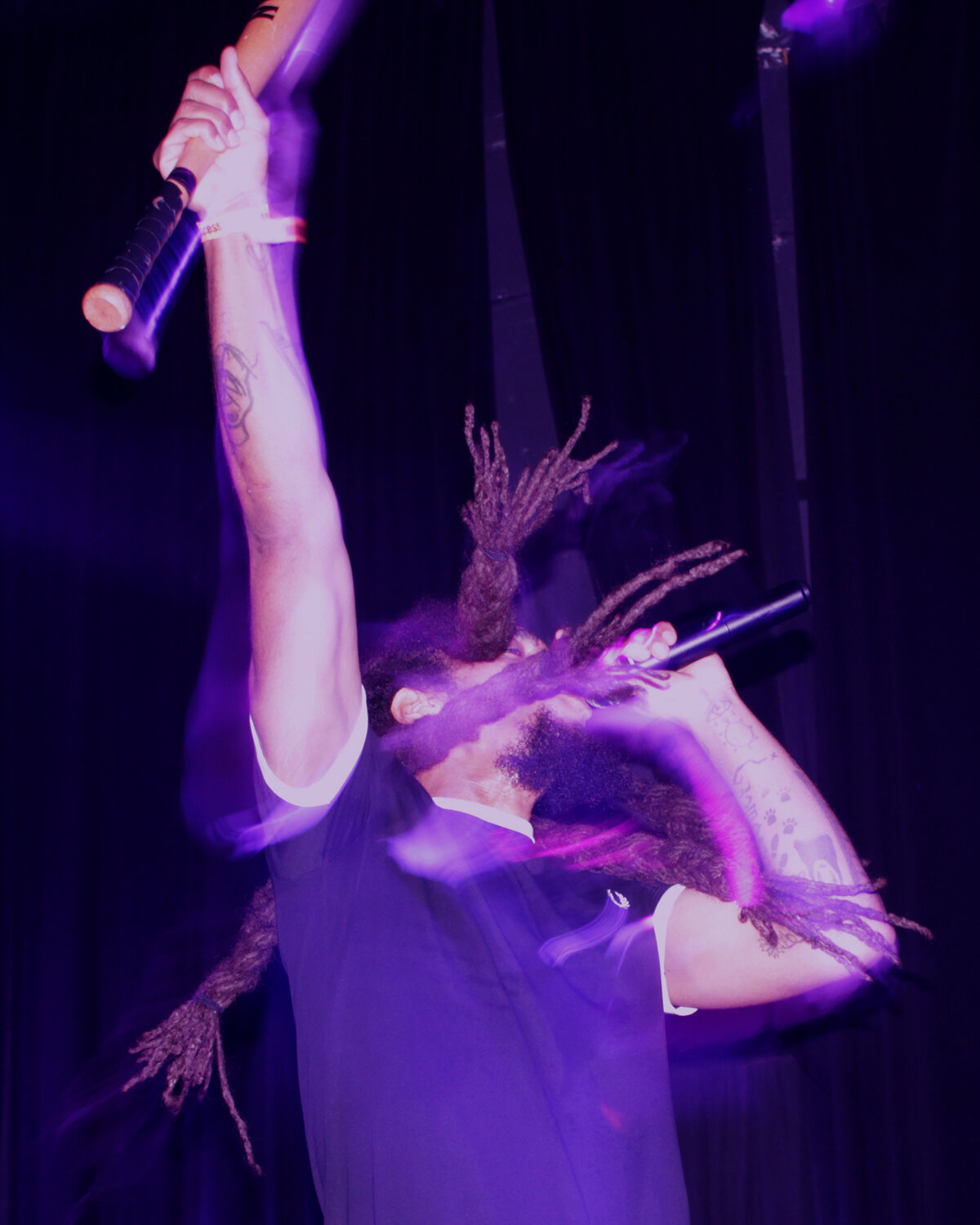 Performer and crowd at an intimate club show with purple-blue stage light