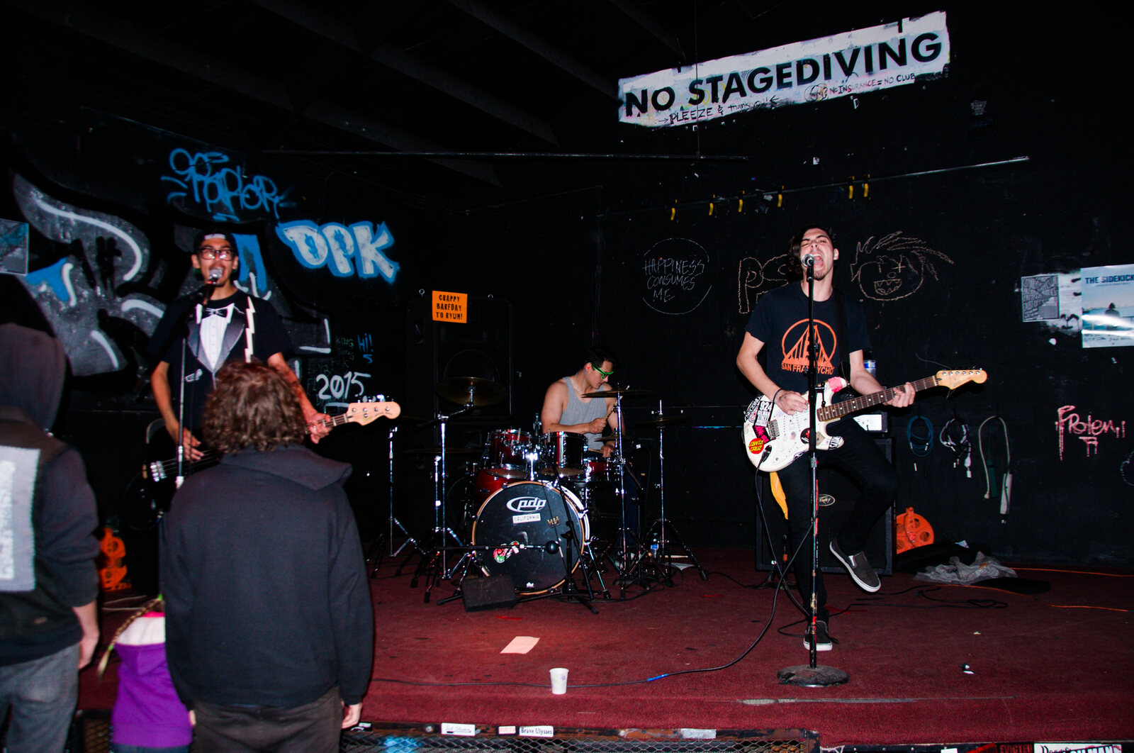 Punk band on stage in a compact venue with audience near the front
